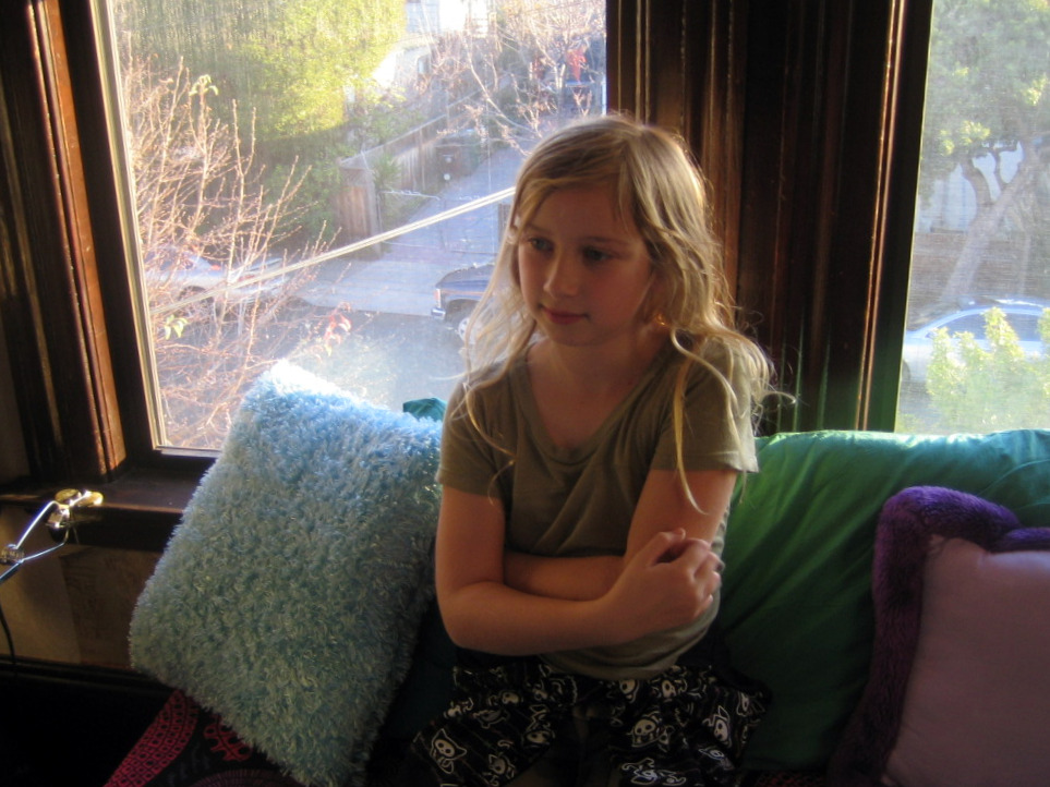 a little girl sitting on a couch holding her phone