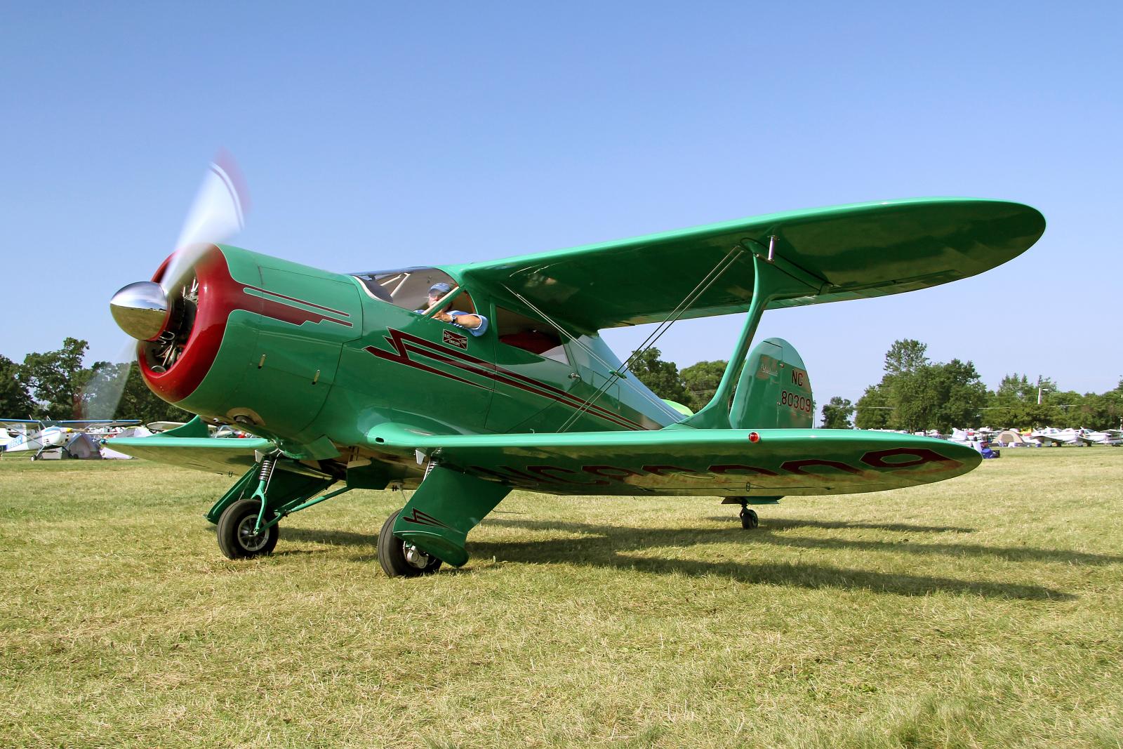 a green plane on the ground with an airplane propeller