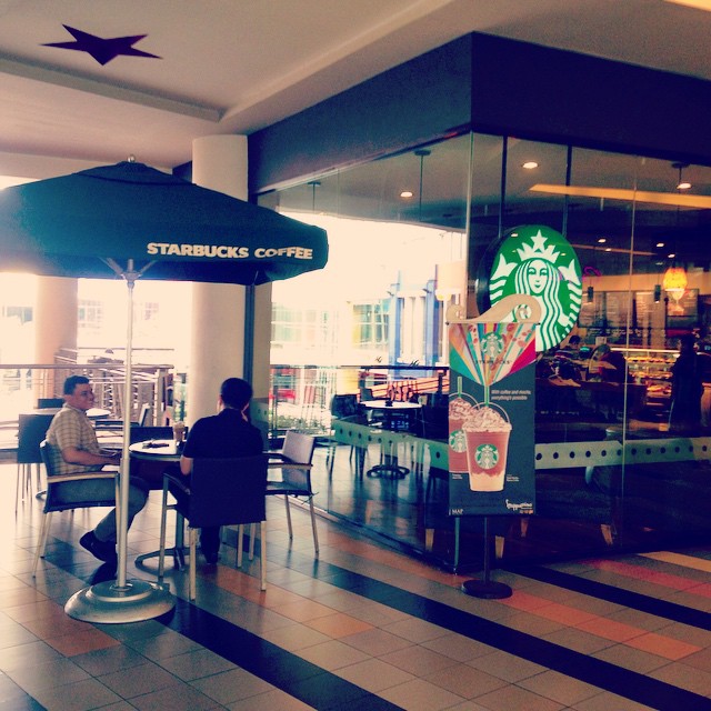 two people sit at an open starbucks coffee shop