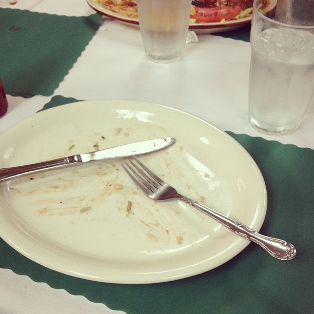 a plate is half eaten with a fork next to some glasses