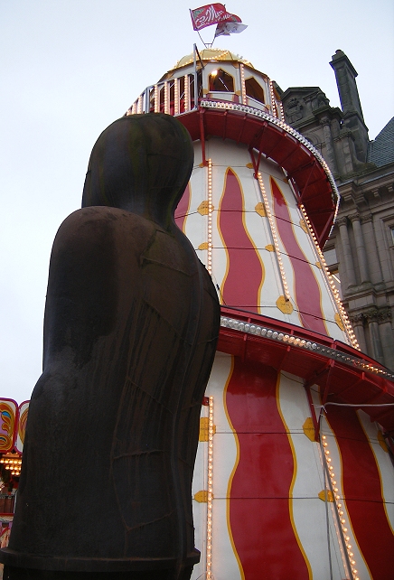 a big statue next to a tower in the background