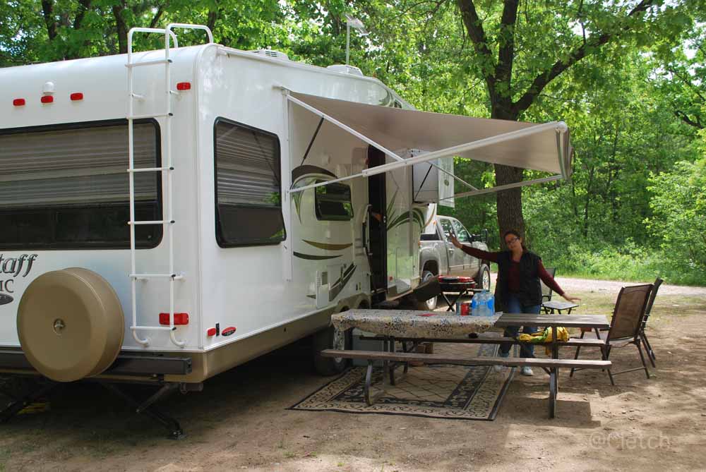 an rv park with a tent, picnic table and picnic chairs