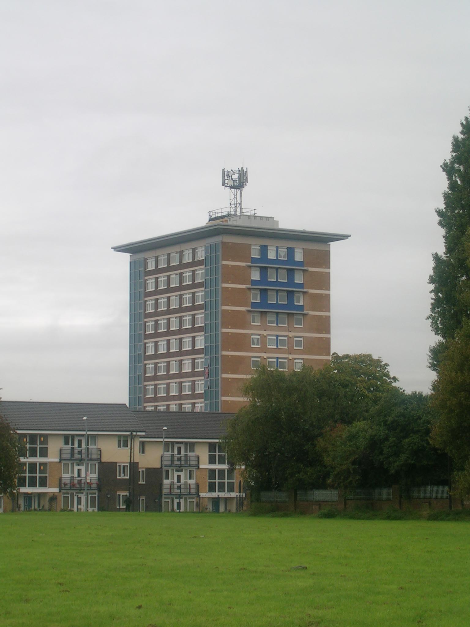 a large brown building with blue windows sitting on top of a green field
