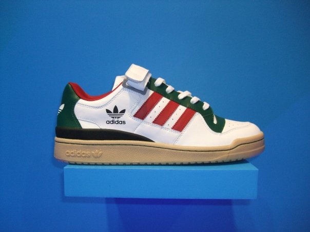 a white, green and red adidas sneaker on top of a stand