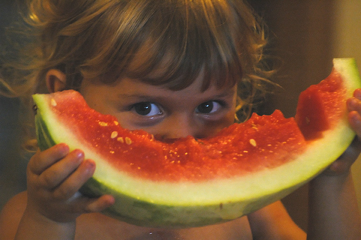 a young child eating a large slice of watermelon