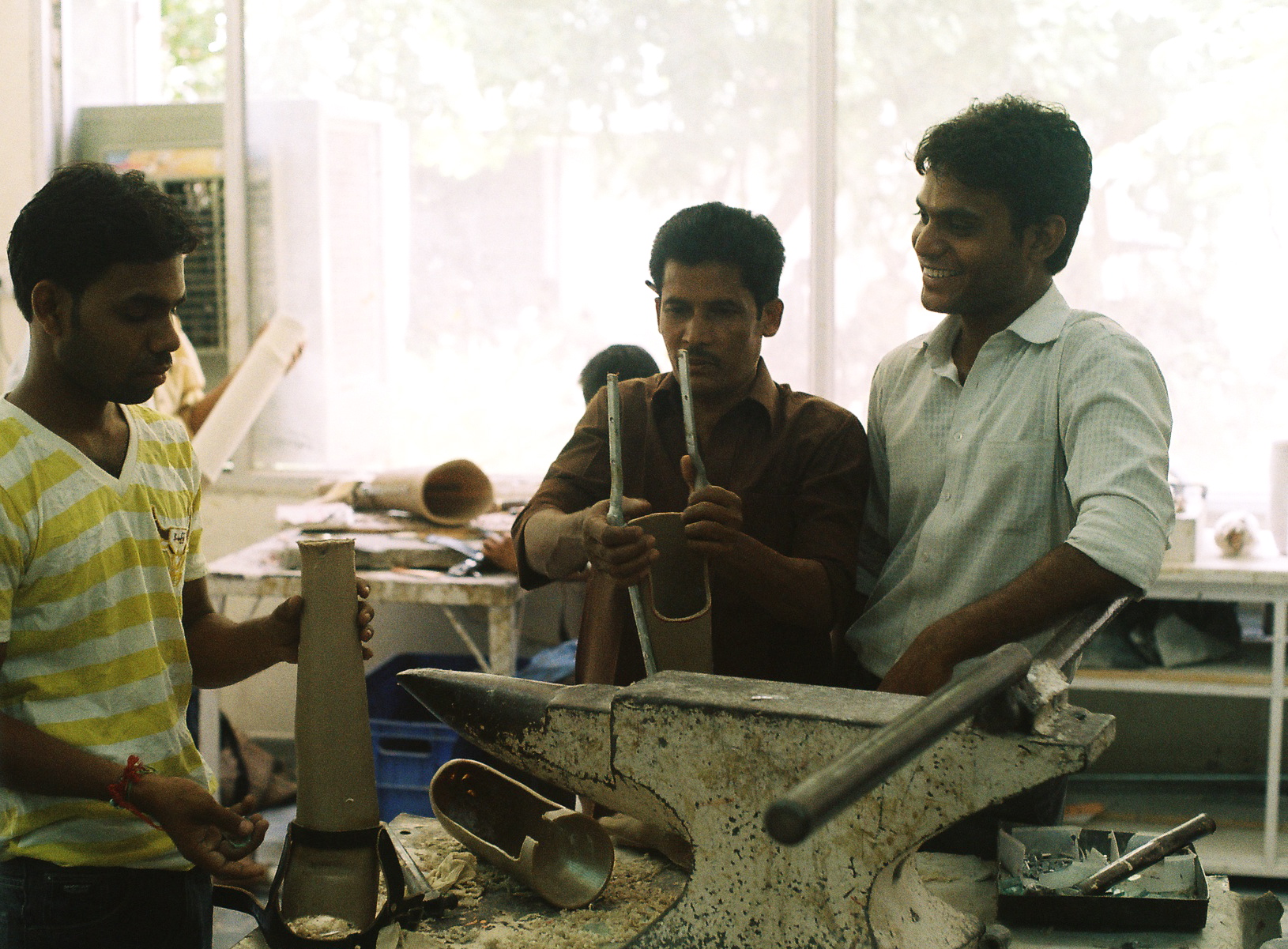 three men working on a sculpture in an artisan shop