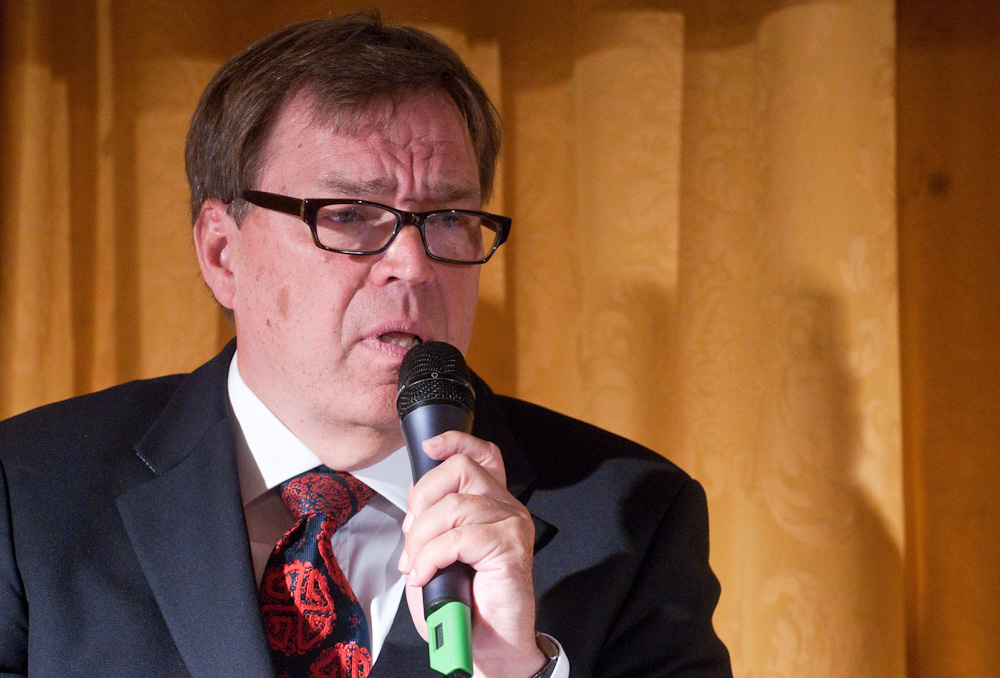 a man in glasses and suit holding a microphone