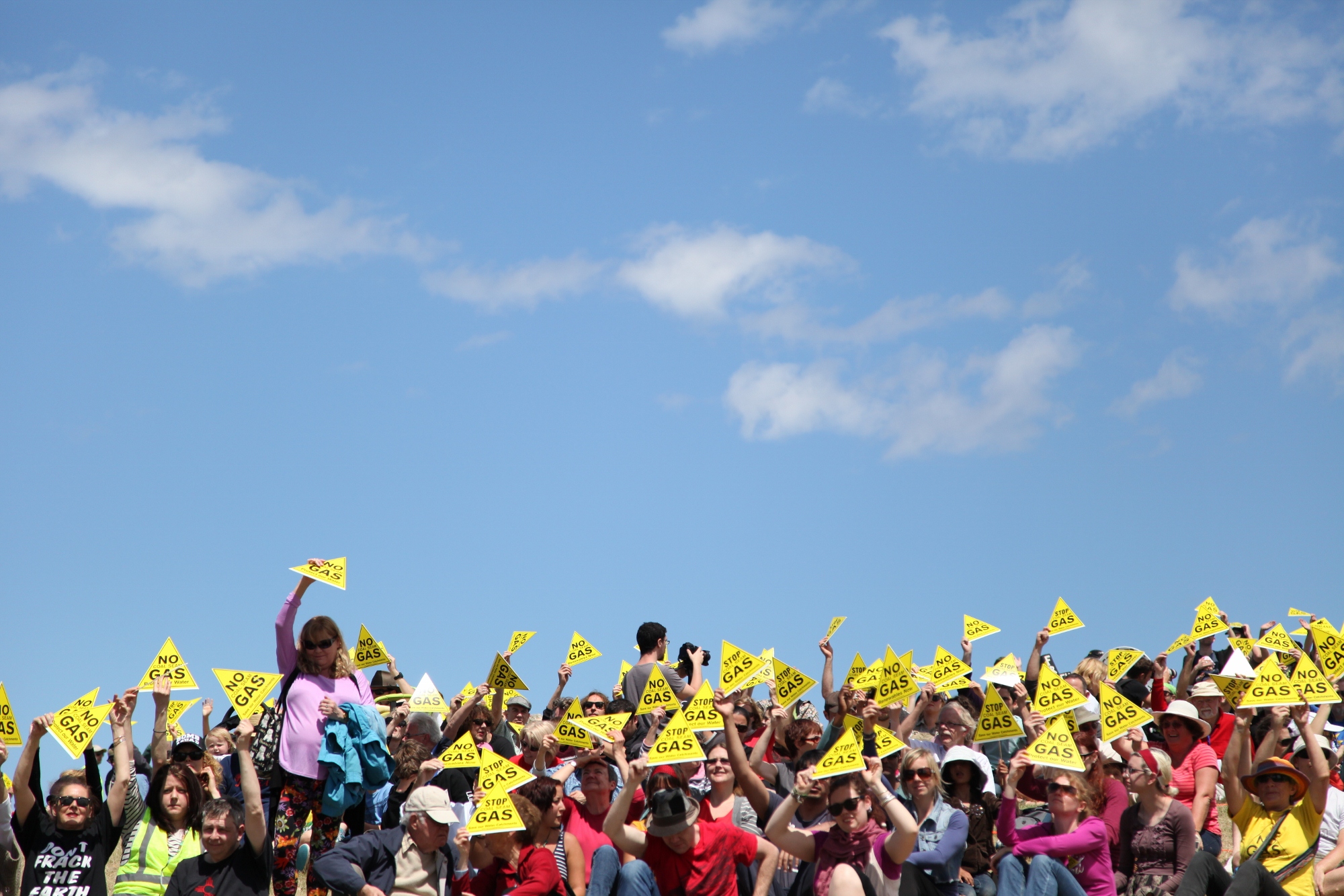 a large group of people are standing together and some are holding yellow signs