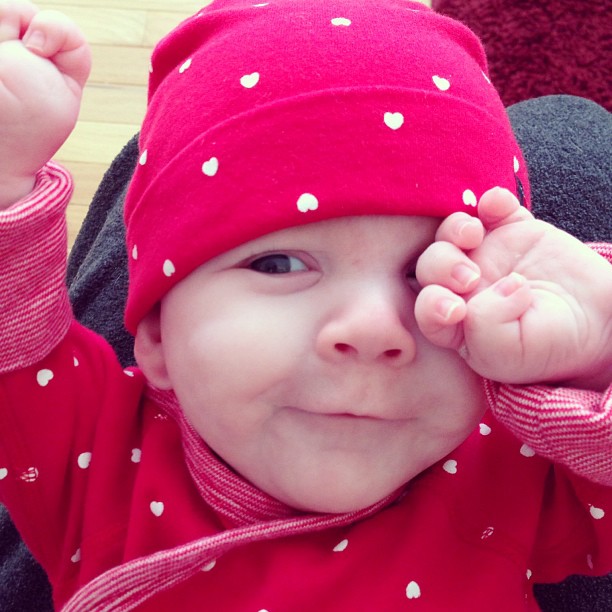the baby is wearing a red hat while smiling