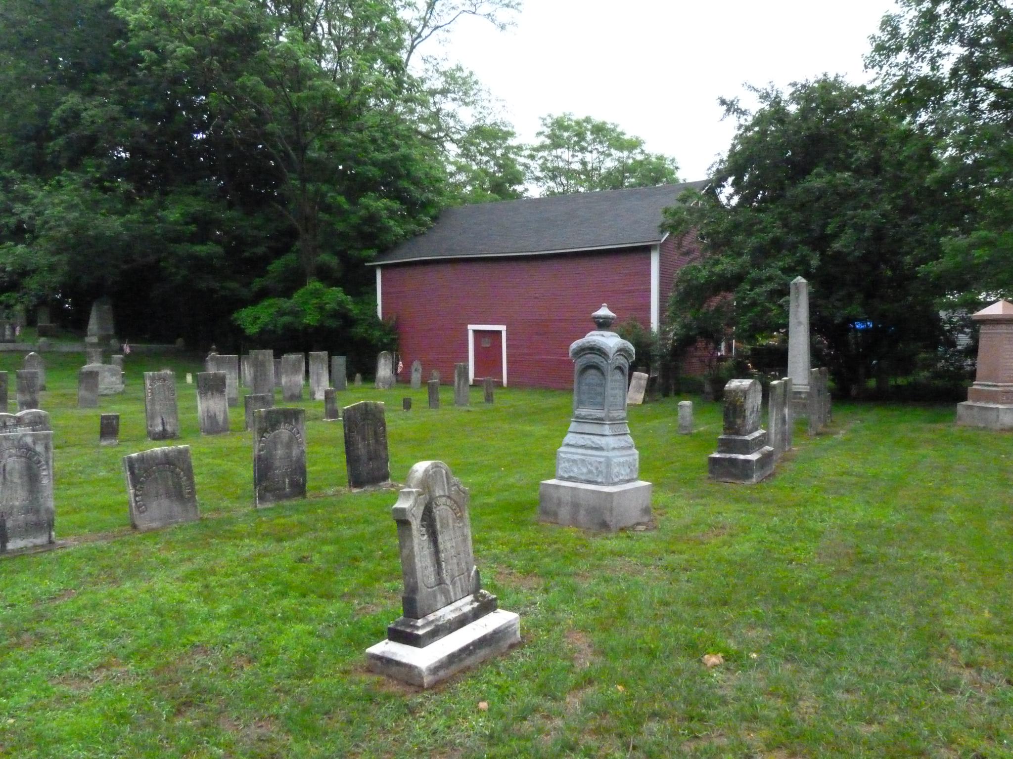 a cemetery with graves in front and a barn in the background