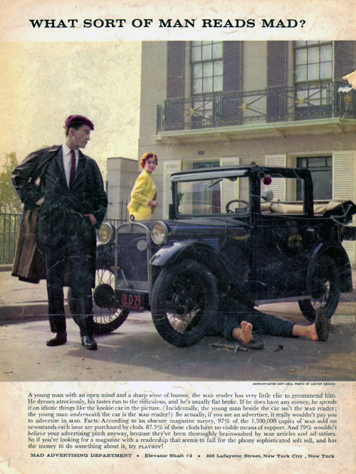 a man laying on the ground next to an old car