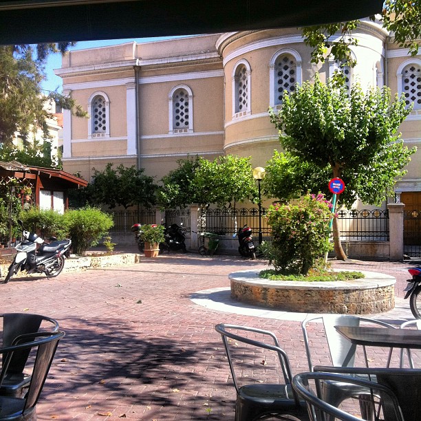 a bunch of chairs and some trees in front of a building