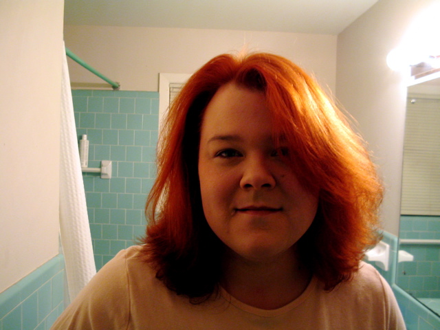 a woman with bright red hair is looking at the camera