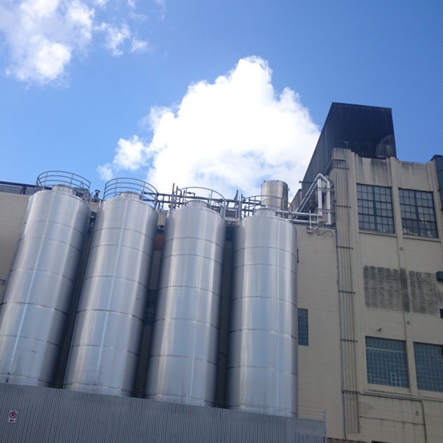 industrial silos next to a large building under cloudy skies