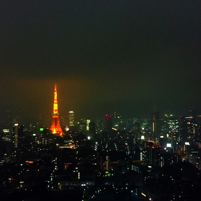 the view of tokyo is shown at night with an orange light on it