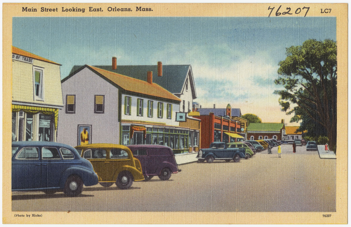 the old time picture shows a street lined with parked cars