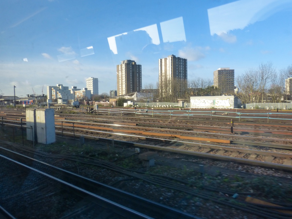 a view of some very tall buildings on the other side of railroad tracks