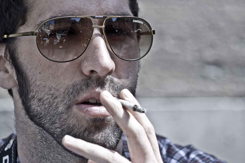 a man in a plaid shirt smoking a cigarette