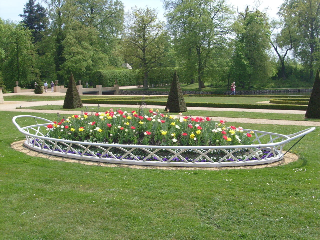 a bench is surrounded by a circle planter with many flowers