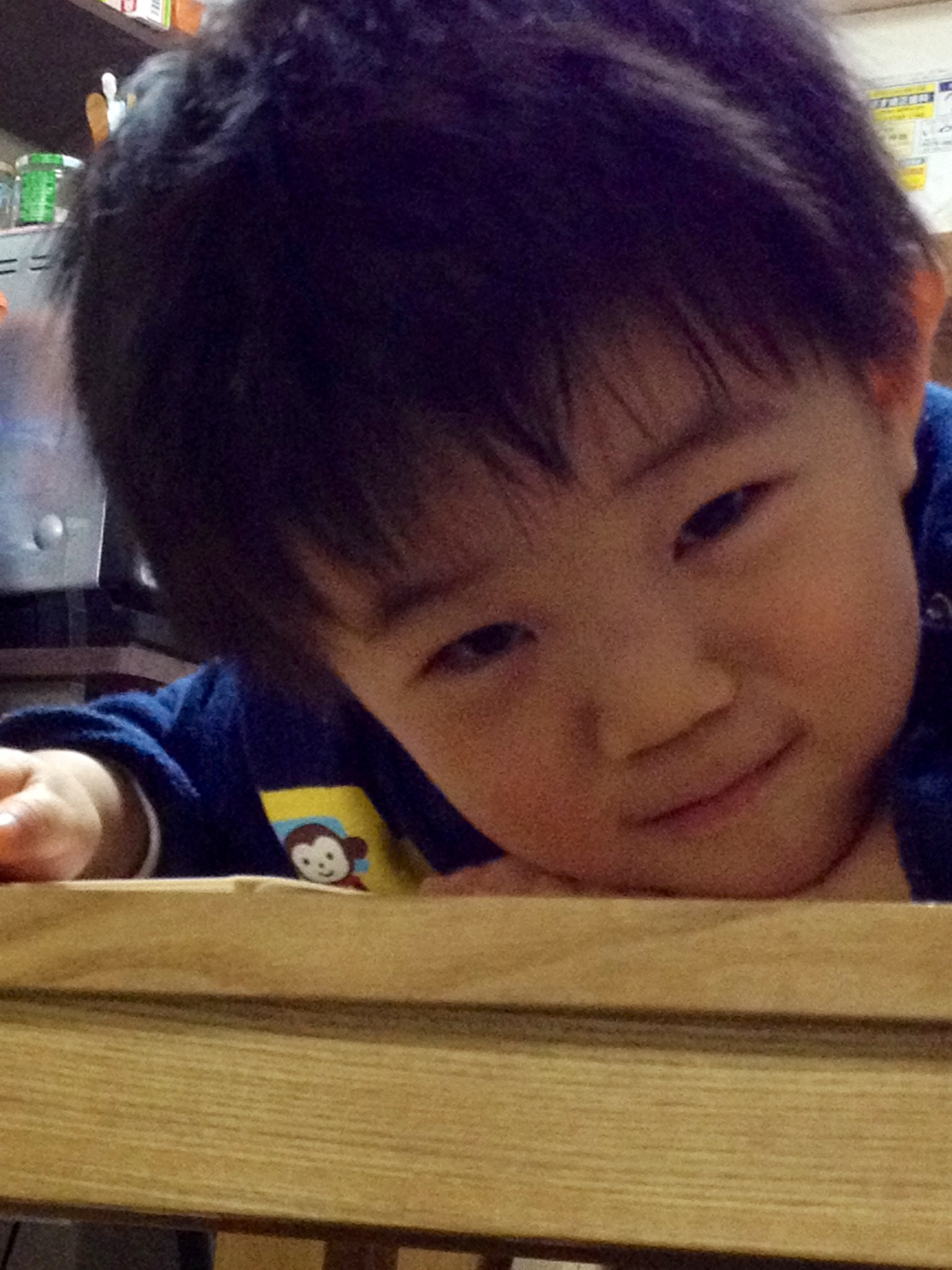 a baby boy in blue shirt leaning over table