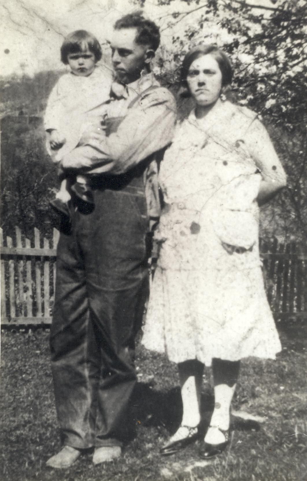 a man holding a baby standing next to his wife