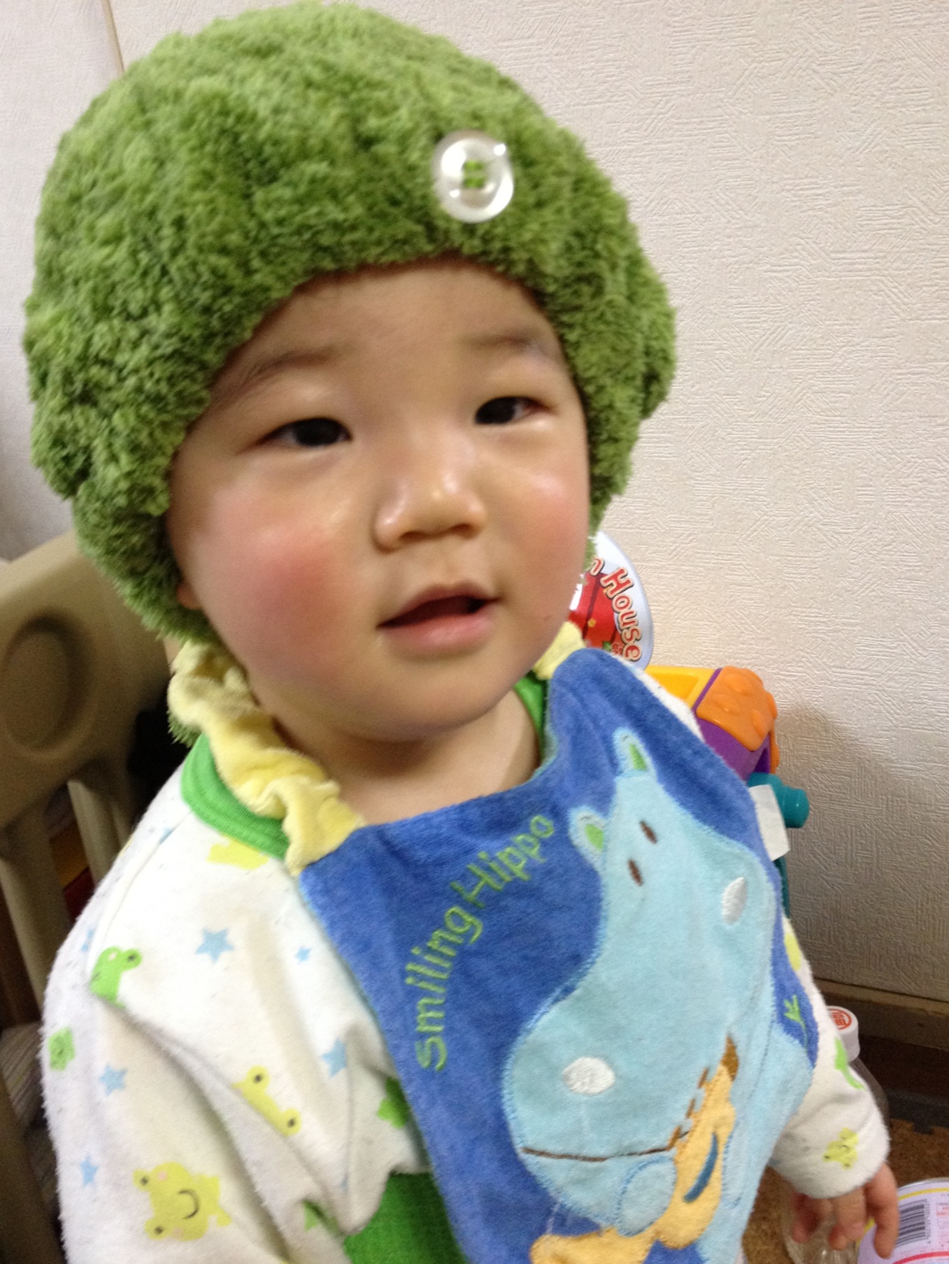 a toddler wearing a hat standing near a door