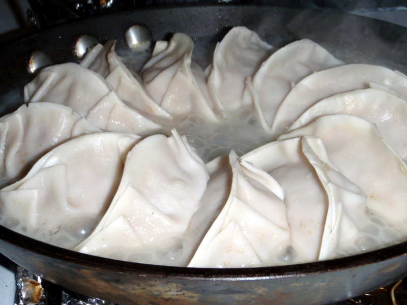 dumplings being prepared in a frying pan on the stove