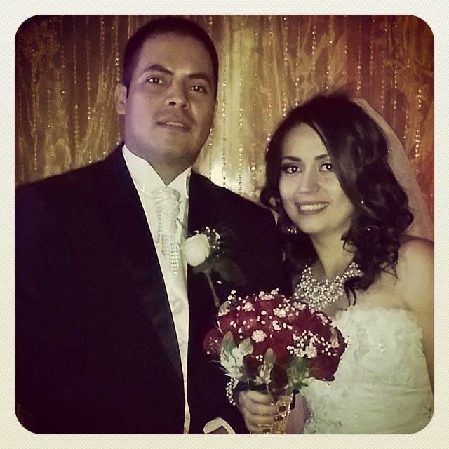 a man and woman in wedding attire with red bouquets