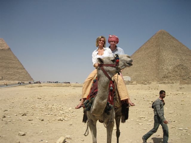 a man riding on the back of a camel near the pyramids