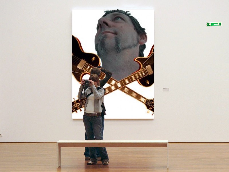 a man is looking at a huge guitar on the wall