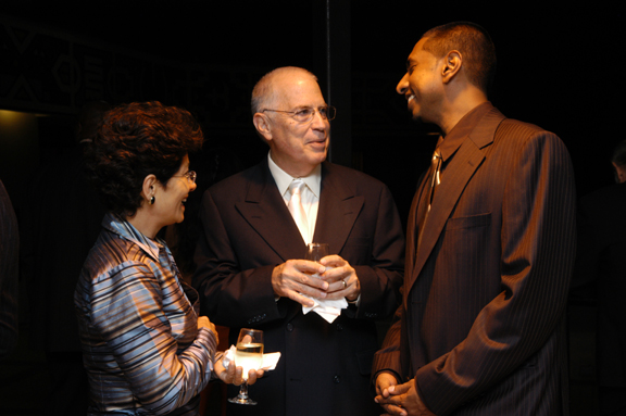 three people standing next to each other holding drinks