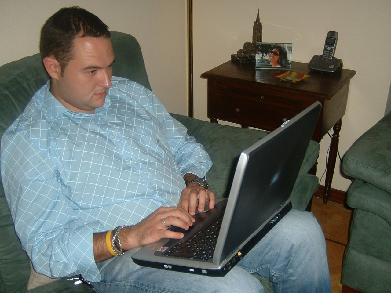 a man sitting on top of a couch working on a laptop