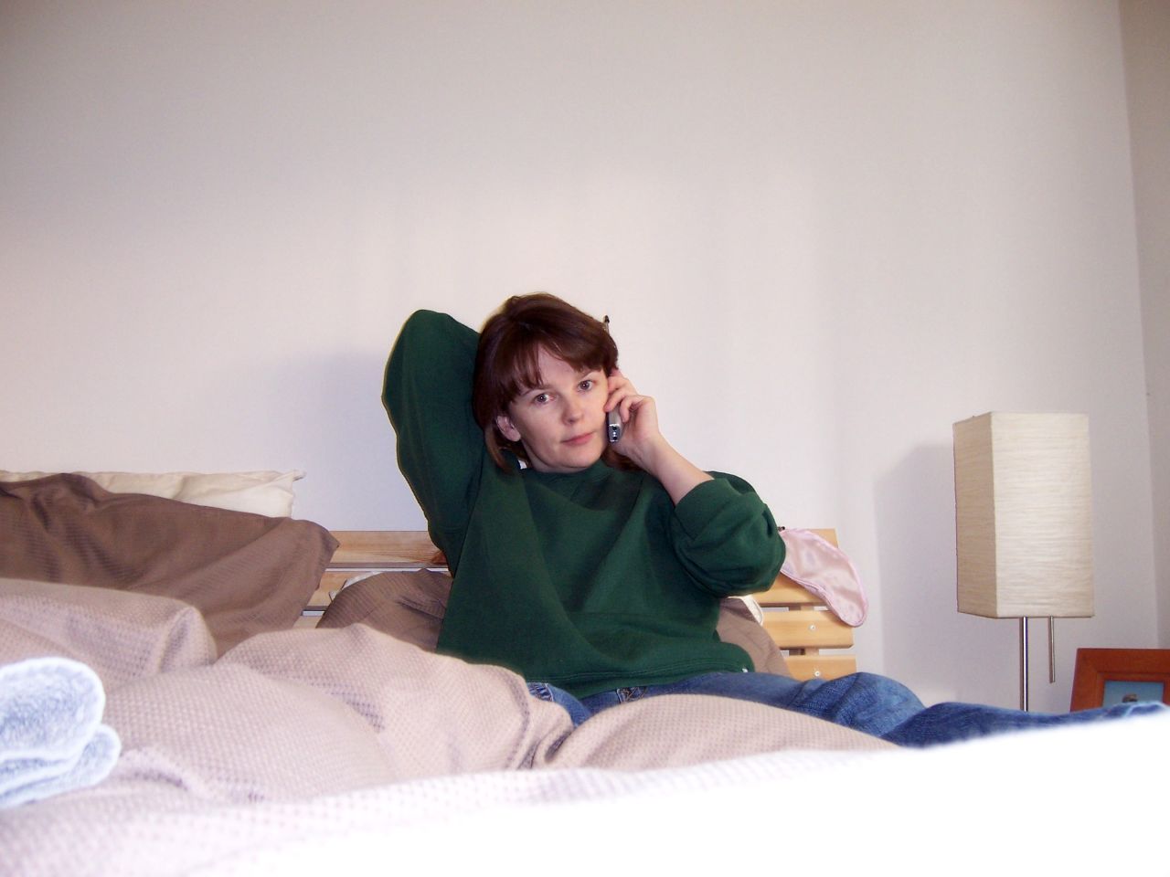 a woman laying in bed talking on her phone