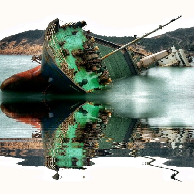 a wrecked ship on the water by a mountain