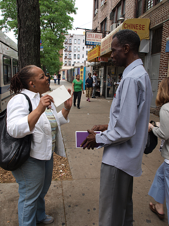 a man holds up a piece of paper as people cross the street