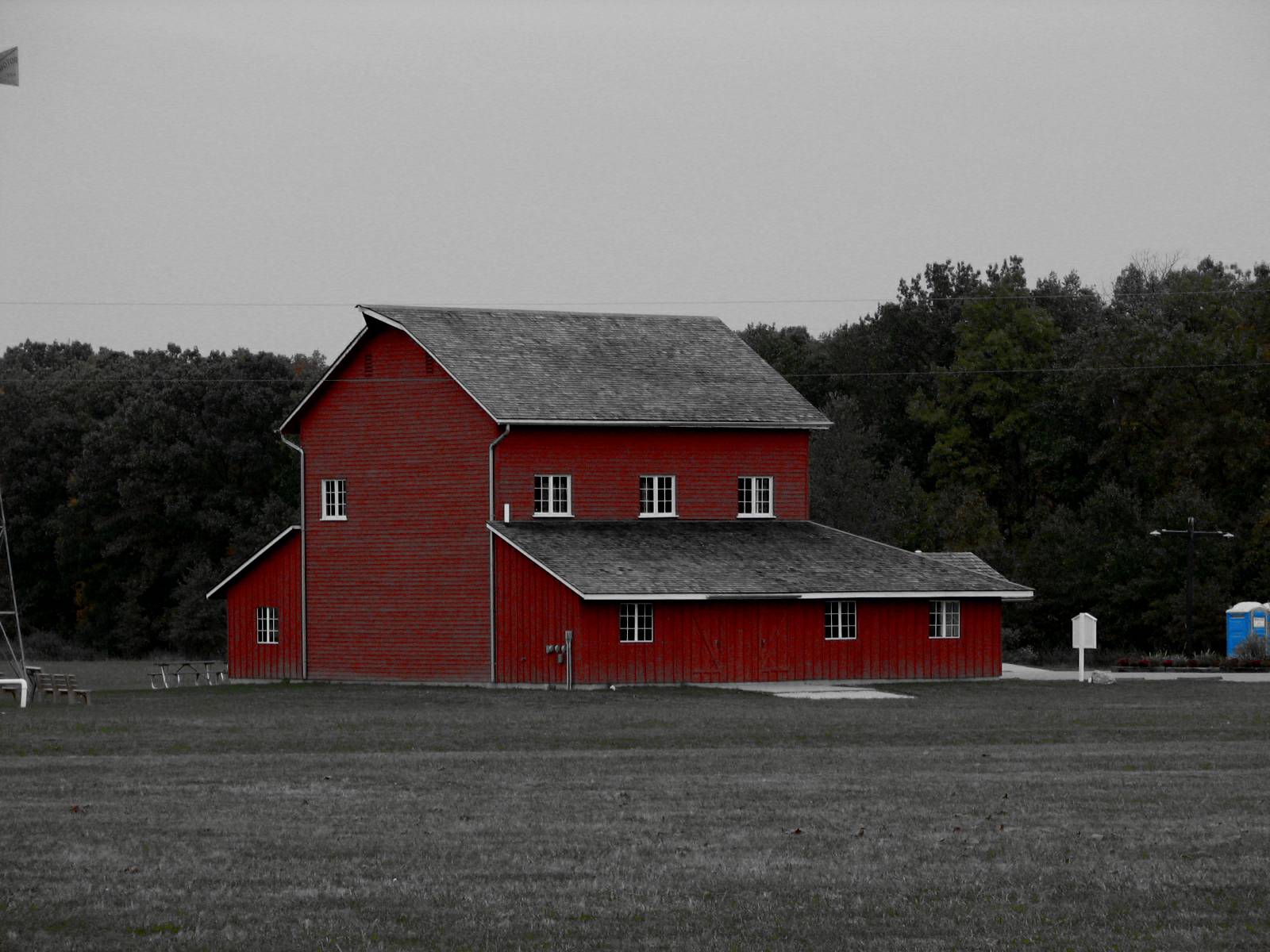 the tall barn is located beside a power pole