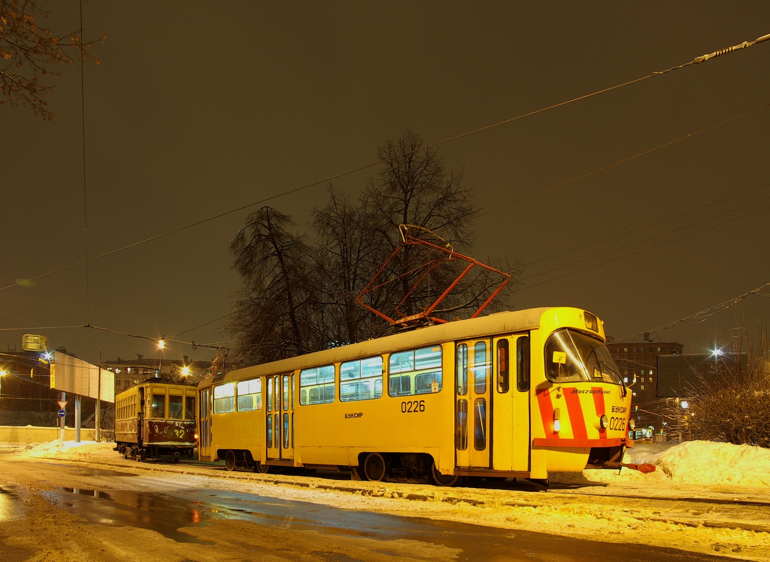yellow trolley parked on snowy street at night