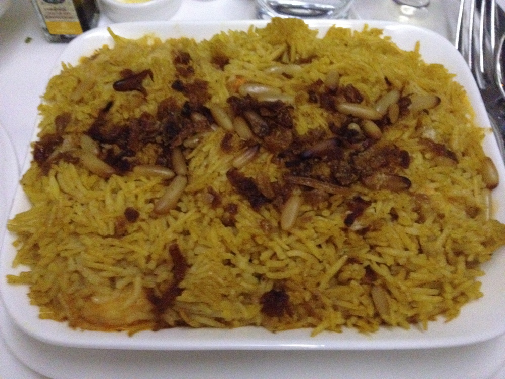 rice in a white plate is served with nuts