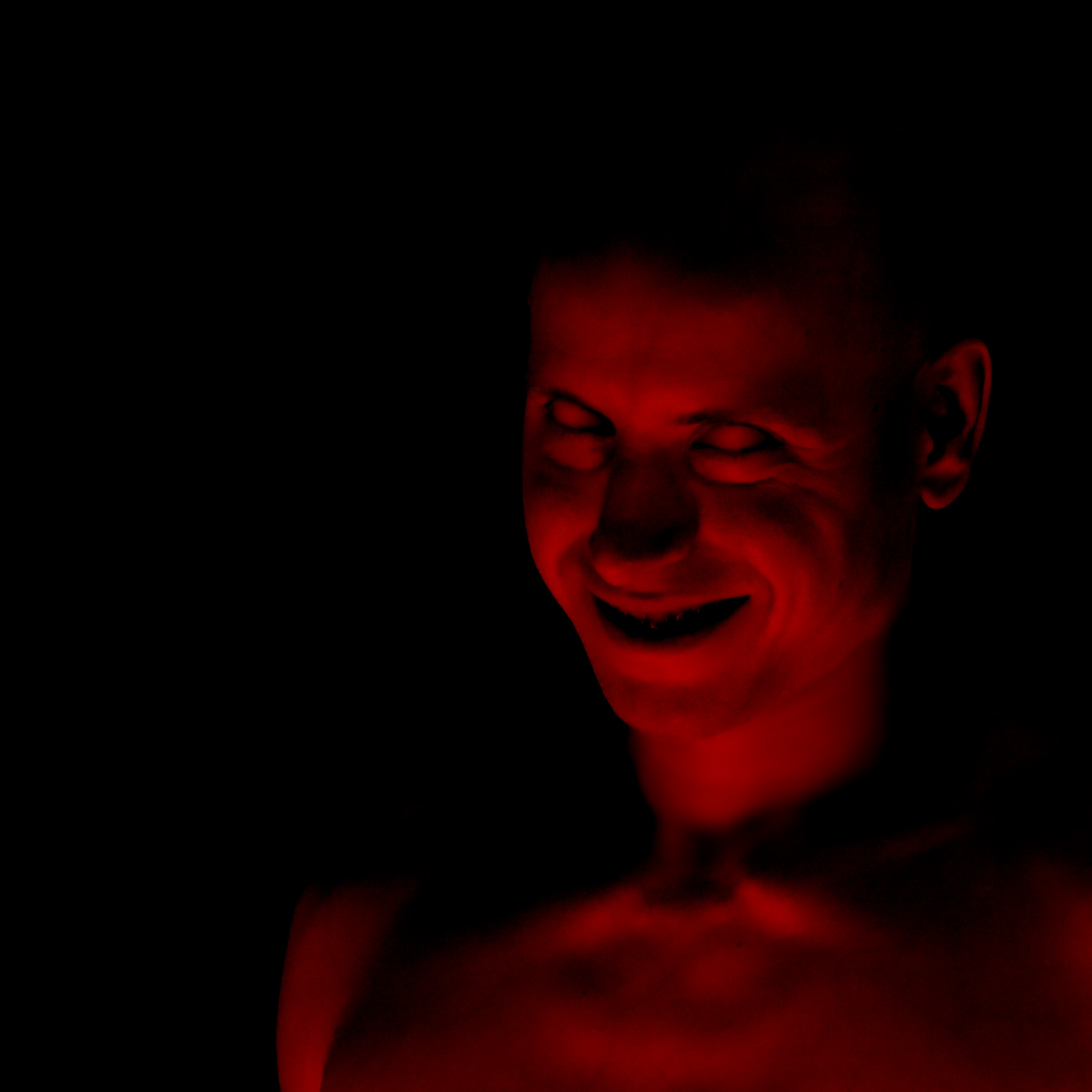a man smiles in a dark po with red light