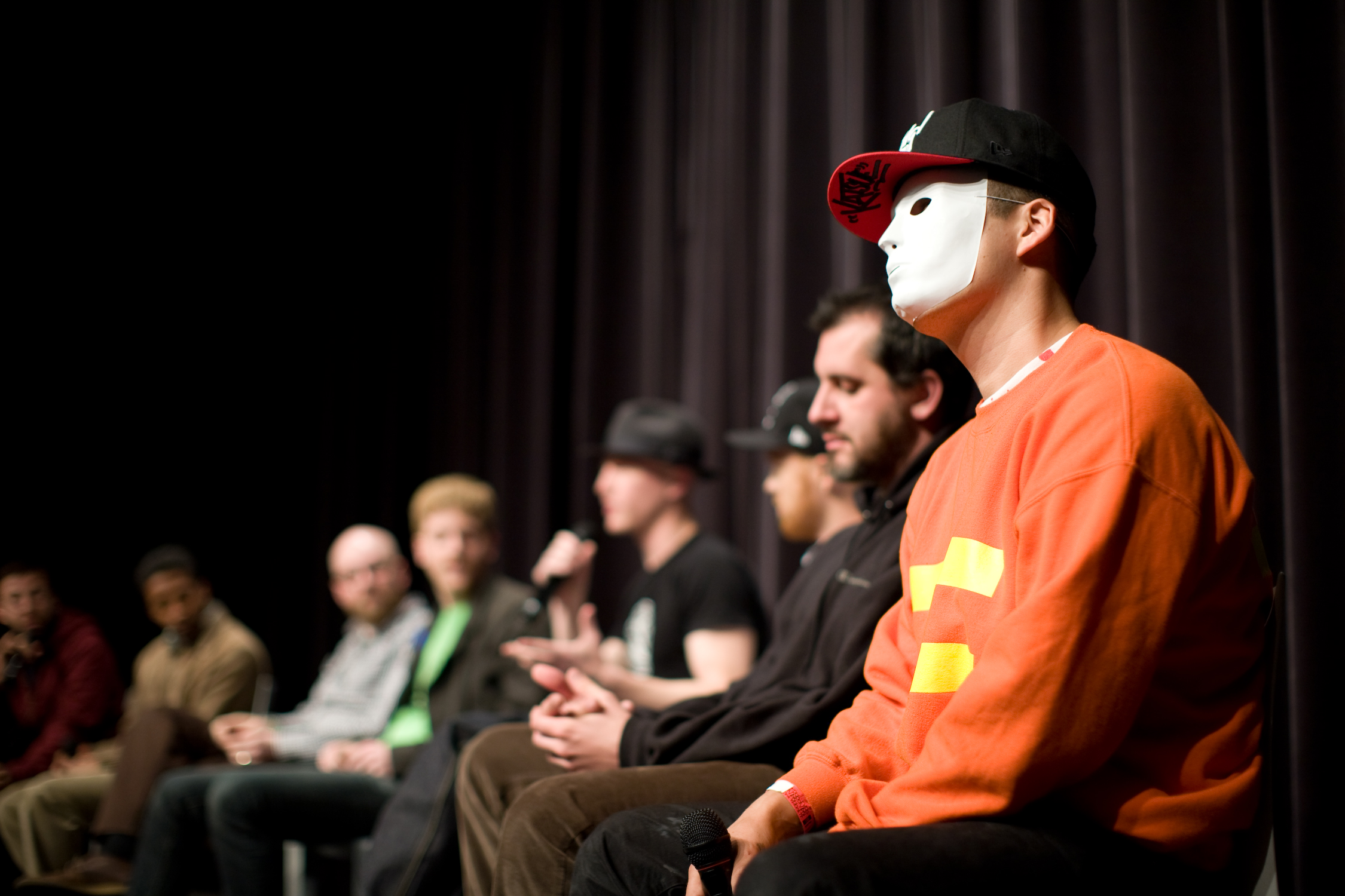 people wearing masks in a darkened room while others watch