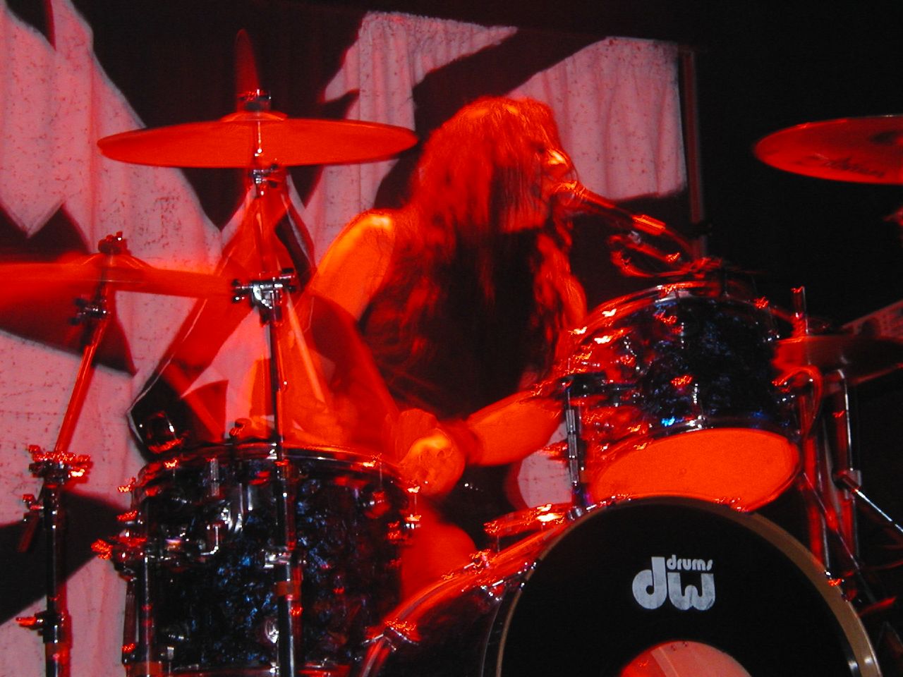 a man with long hair playing a drums set