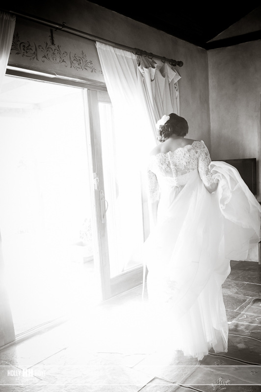 a woman in a gown stands looking out the window