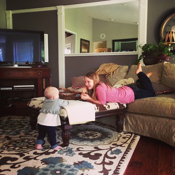 a woman lying on a couch playing with a toddler