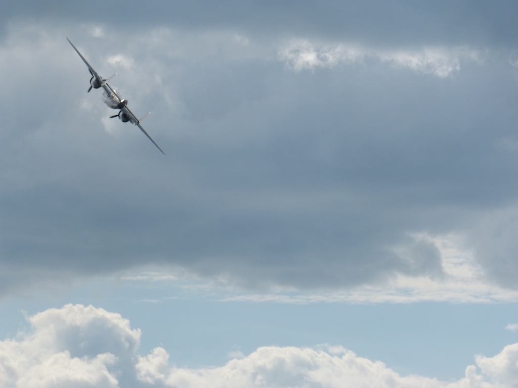 a small plane flies through the blue cloudy sky