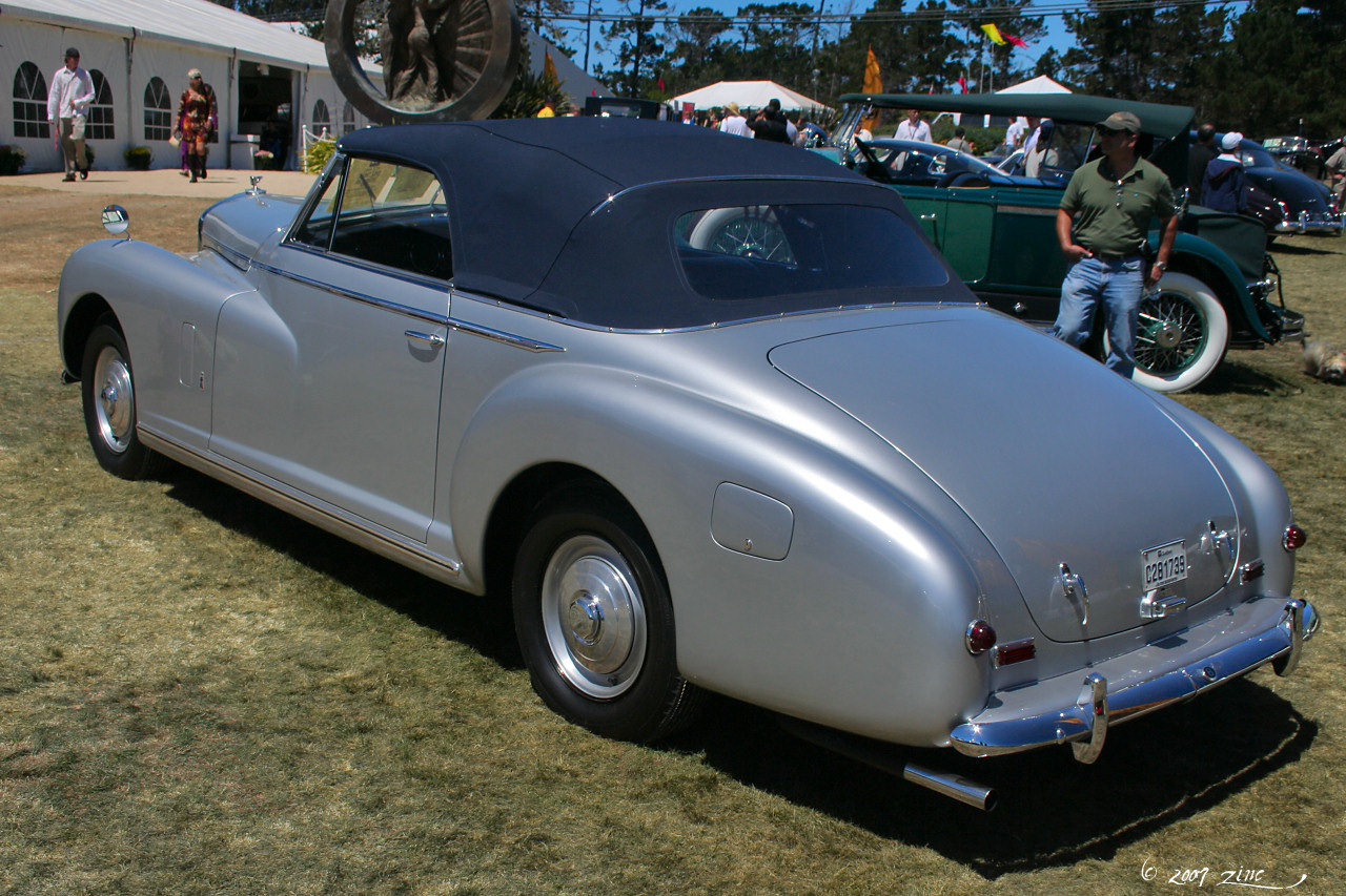 a silver vintage car parked on a grass field