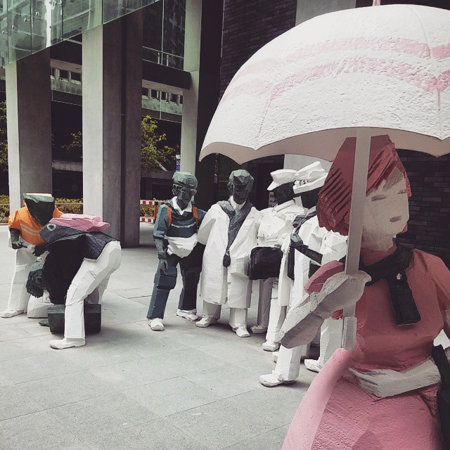 a group of sculptures in front of a building holding an umbrella