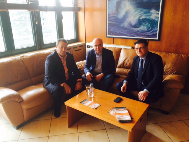 three men sitting in front of a wooden coffee table