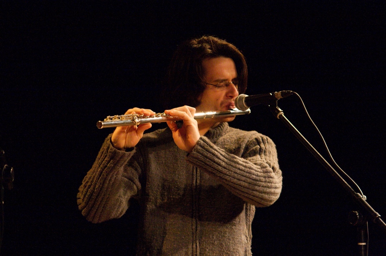a man standing in front of a microphone playing flute