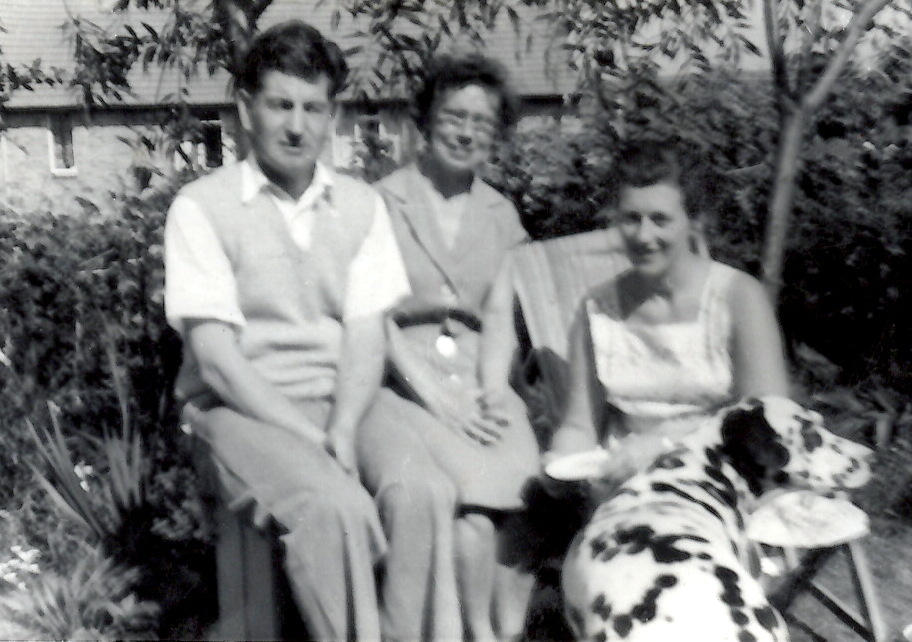 black and white po of people sitting on a bench with their dog