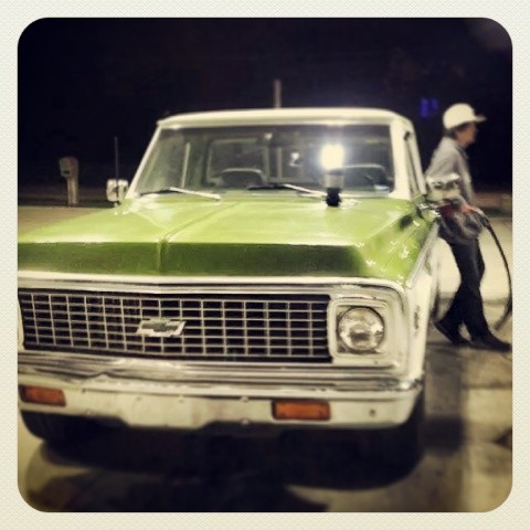 a green pick up truck parked on top of a wet cement floor